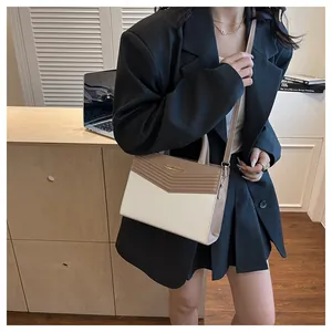 Detail of contrast color crossbody bag with gold logo shown on an office worker model