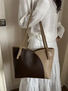 Large contrast-color tote bag in brown leather on model, stylish shoulder handbag for work