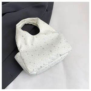Vue détaillée du sac à main croissant blanc avec motifs d'étoiles argentées et texture cuir