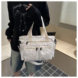 Detailweergave van de canvas tas met bloemenprint, drie ritszakken en verstelbare riem