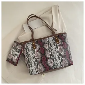 Détail du sac cabas motif serpent avec rivets dorés et pochette assortie incluse