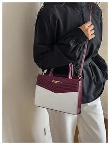 Detail of contrast-color crossbody bag with V-shaped stitching and golden metal logo
