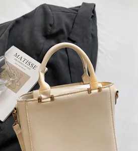 Detail of cream faux leather handbag with sturdy handles and gold metal hardware