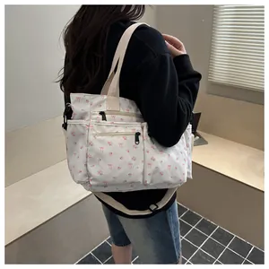 Bloemen canvas draagtas met roze strikken en verstelbare riem getoond op een model