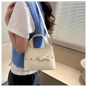 Detail of cream soft leather bucket bag featuring bow decoration and metal eyelets