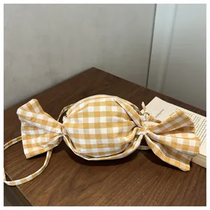 Λεπτομέρεια τσάντας χιαστί με σχέδιο gingham σε σχήμα καραμέλας πάνω σε ξύλινο τραπέζι