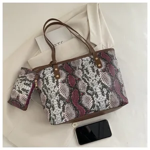 Détail du sac cabas imprimé serpent avec lanières en cuir brun et petite pochette