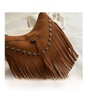 Detail of brown suede bohemian fringe bag featuring silver metal rivets and long tassels