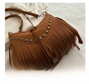 Detail of brown suede crossbody bag with metallic studs and stylish long fringes