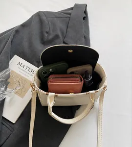 Detail showing spacious interior of beige crossbody bag with phone and wallet