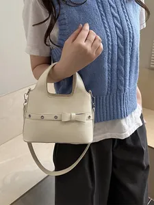 Cream vintage soft leather bucket shoulder bag with decorative bow and metal eyelets