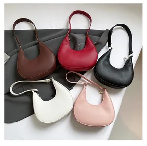 Flat lay of crescent underarm bags in five colors with lychee texture and gold hardware