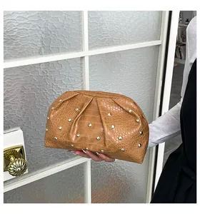 Detalle de bolso de mano marrón plisado con textura de cocodrilo y remaches dorados