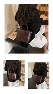Detail of dark brown glossy leather handbag showing handle and detachable shoulder strap