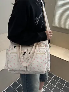 Bloemen canvas draagtas met roze strikjes en groot multi-pocket ontwerp getoond op model