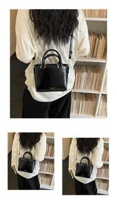 Detail view of glossy black leather handbag with gold hardware and shoulder strap