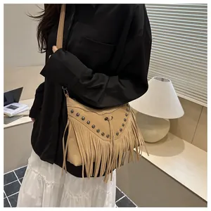Detail of bohemian camel suede crossbody bag featuring vintage metal rivets and long tassels