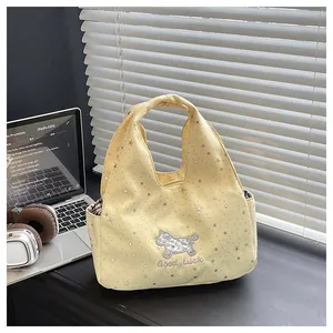 Détail du sac à main en tissu jaune clair avec étoiles argentées et broderie de chiot