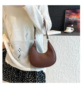 Detail of brown hobo bag showing litchi grain texture and gold hardware on shoulder strap