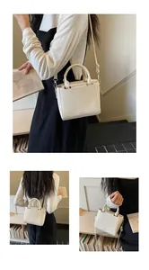 Detail of cream white leather square handbag with golden hardware and dual top handles