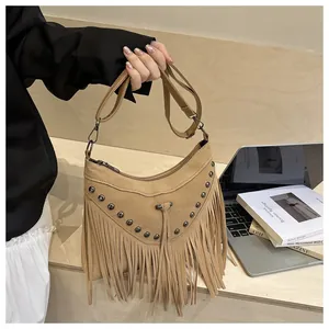 Detail of khaki suede crossbody bag with metal rivets, fringes and adjustable strap