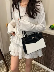 Elegant black and white leather handbag with V-shape design and golden metal hardware