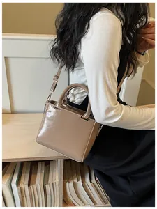 Detail of glossy khaki shoulder bag with gold hardware and curved handle in lifestyle setting