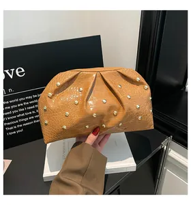 Detalle de bolso de mano caramelo con textura de cocodrilo y tachuelas doradas