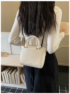 Cream white shoulder bag displayed on shoulder in a cozy indoor minimalist library setting