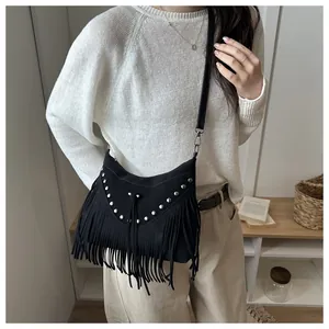 Detail of bohemian black suede crossbody bag featuring silver rivets and long fringes