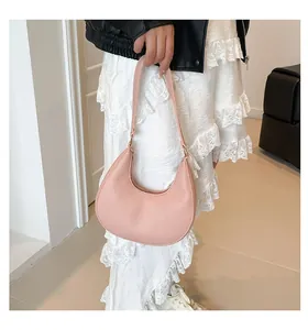 Pink pebble leather crescent shoulder bag shown on a model in a minimal setting
