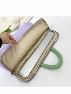 Detail of the purple quilted laptop sleeve showing internal capacity and green handles