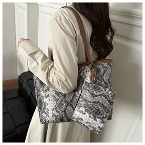 Détail d'un sac cabas imprimé serpent avec pochette assortie et anses en cuir fin