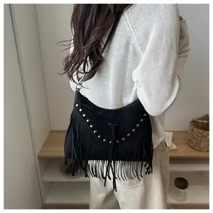 Detail of bohemian black suede half-moon bag featuring metallic rivets and long tassels