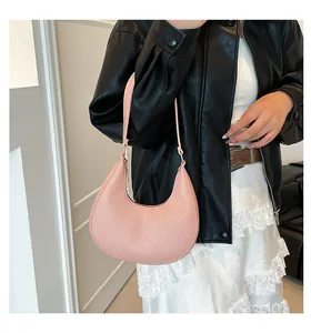 Close-up of pink crescent hobo bag with pebble leather texture worn on the shoulder