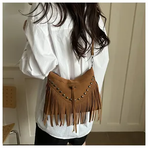 Detail of brown suede crossbody bag with bohemian fringe and vintage metal rivets