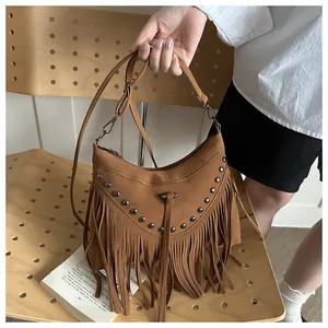 Close-up of brown bohemian fringe bag with metallic rivets and suede texture details
