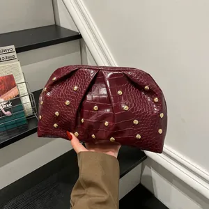 Bolso de mano granate con relieve de cocodrillo, pliegues y remaches dorados elegantes