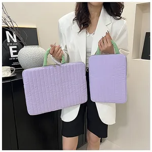 Quilted lilac laptop sleeve with green handles held by a woman in a white suit