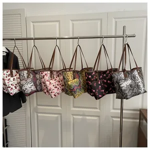 Série de sacs cabas aux motifs de cerises et textures serpent sur un cintre en métal