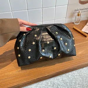 Elegante bolso de mano negro de cocodrilo con remaches dorados y silueta de nube plisada
