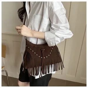 Detail of bohemian crossbody bag with long fringes and silver rivets on dark brown suede