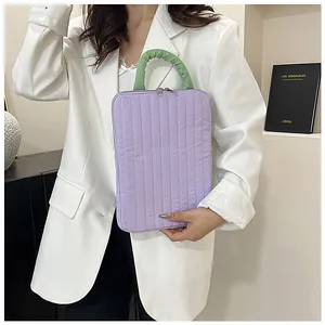 Quilted lavender tablet sleeve with green ruched handle carried by a model in a suit