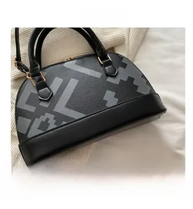 Close-up of black shell handbag with grey geometric pixel patterns and gold zipper