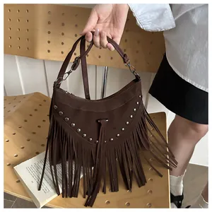 Detail of dark brown suede crossbody bag with silver rivets and long fringe accents