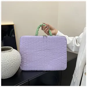 Detail of light purple quilted laptop bag with green ruched handle and dual zippers