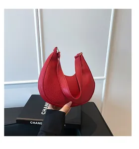 Detailed macro view of the red lychee pattern leather on this half-moon shoulder bag