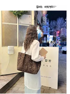 Outdoor street view of a large leopard print tote bag worn on a woman's shoulder