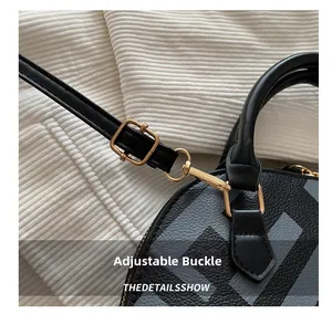 Detailed macro view of the adjustable golden buckle and black pebble leather bag strap