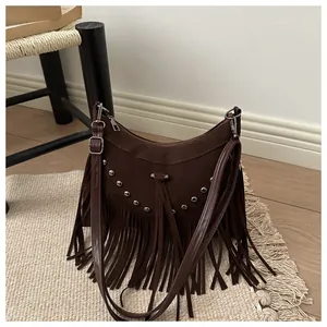 Detail of dark brown bohemian crossbody bag featuring silver rivets and long fringe tassels